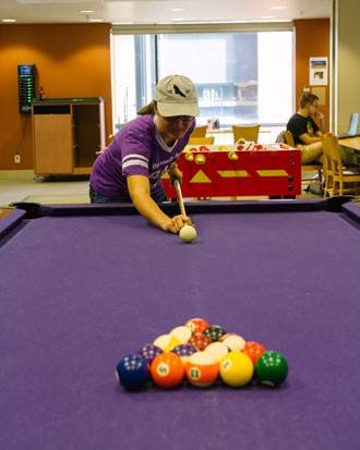 Cornell student hangs out in the Thomas Commons playing pool