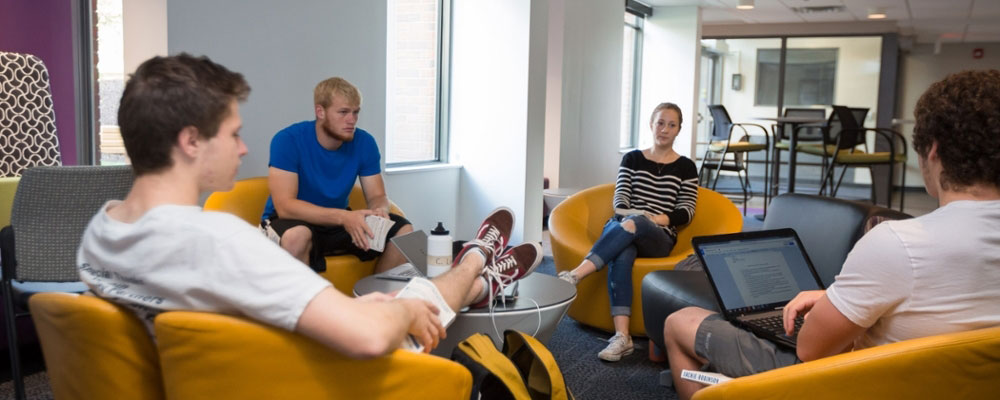 Cornell students sitting in the common space in a residence hall in a discussion.