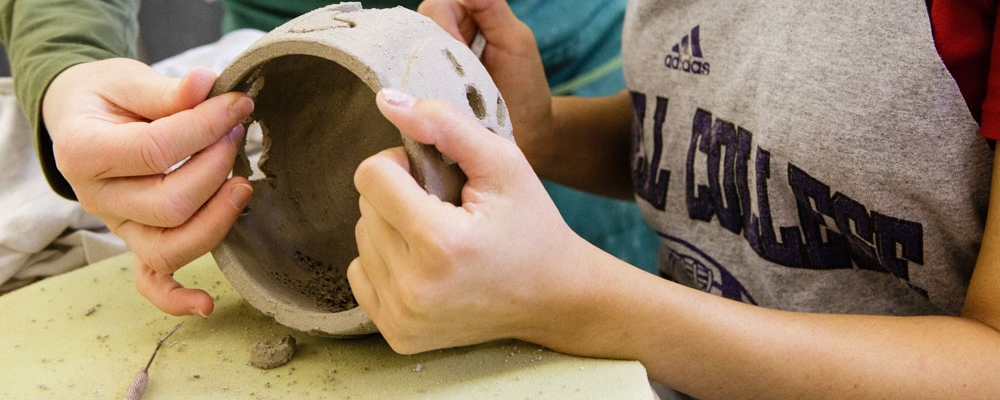 Faculty and a student work on a ceramics project together