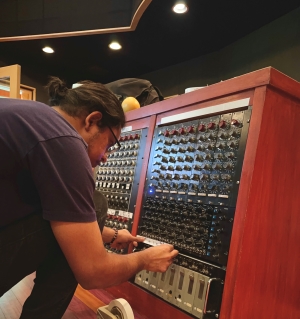 Student kneeling next to audio equipment during internship.