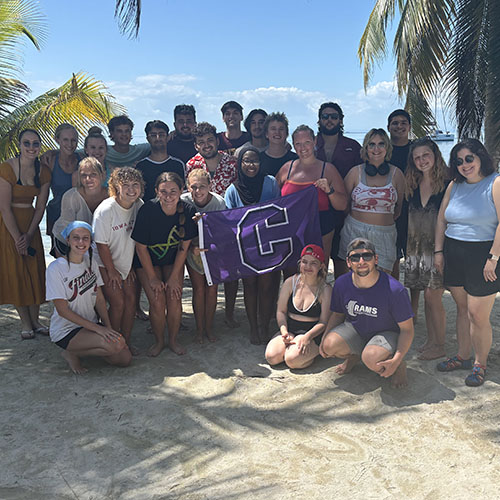 Off-campus study students pose with a Cornell flag in Belize