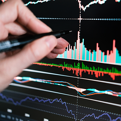hand with a pen pointing at data trends on a computer screen