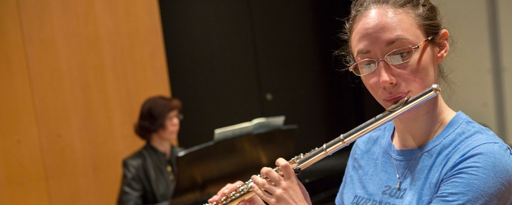 Music student performs on flute while instructor plays piano