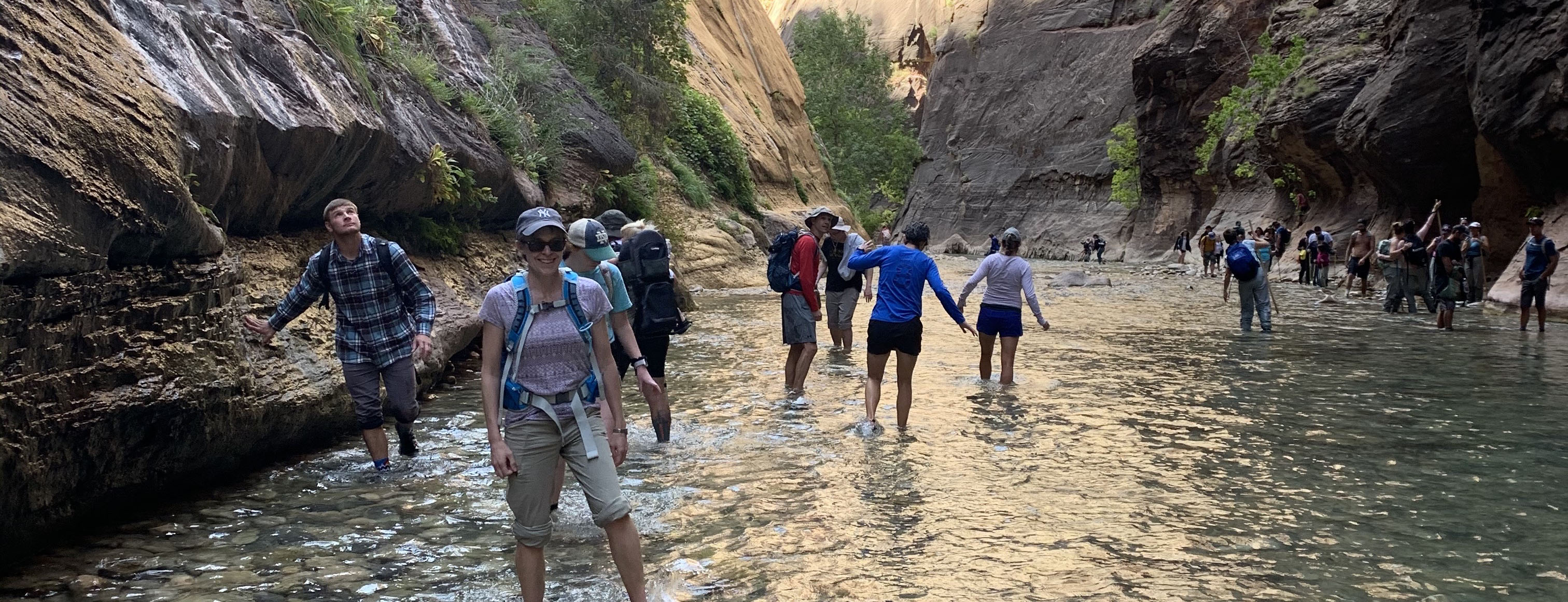 Geology and professor and students hiking in canyon bed.