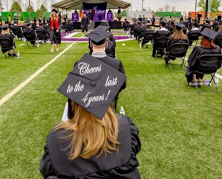 Cornell students at Commencement (graduation) featuring one student wearing a mortarboard that says, "Cheers to 4 years"