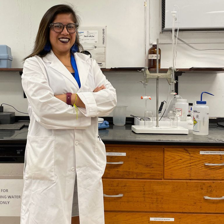 Cornell alumnus wears a white lab coat in her lab