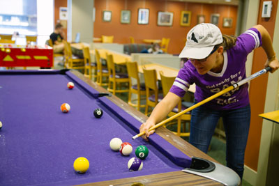 Cornell College student plays pool in a lounge space on campus.
